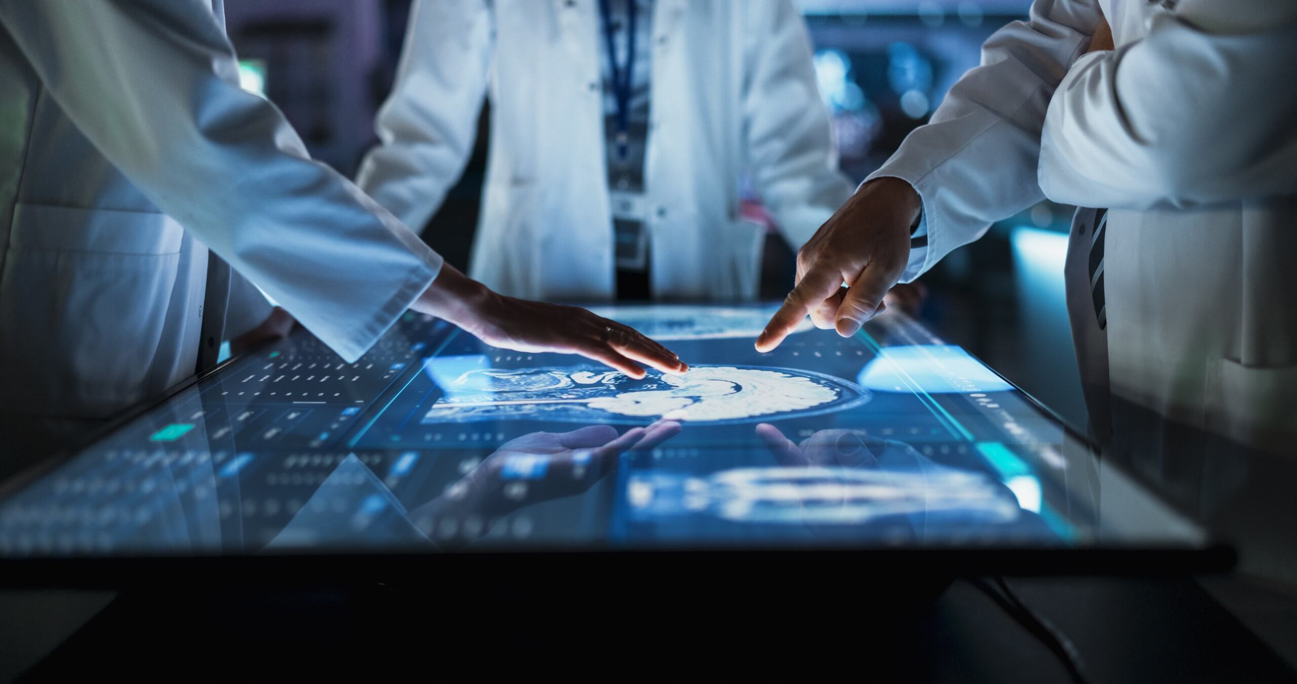 Healthcare professionals reviewing medical information on a digital display.